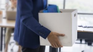business concept : An unemployed with her cardboard box walking out of the work office
