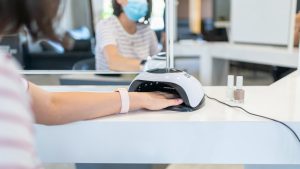 Female Customer Putting Hand İnto UV Lamp Dryer İn Beauty Salon