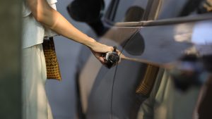 Woman hand on grey car door handle.