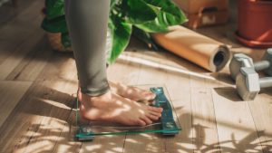 A young woman is weighing herself in a weighing scale