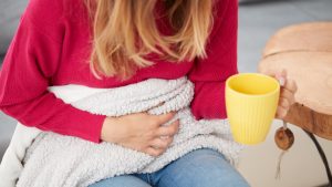 Sick girl holding cup and drinking coffee / tea on a couch.
