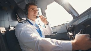 Male airplane captain speaking to ground control through microphone