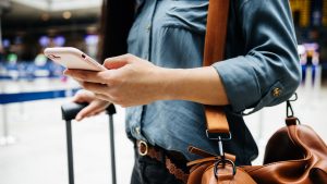 Close Up Of Woman Looking At Smartphone To Find Flight Details In An Airport