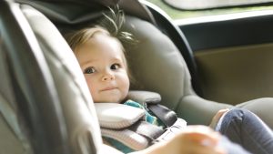 Baby girl (12-17 months) sitting in baby car seat during car trip