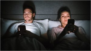 Una pareja mira el móvil completamente distanciada