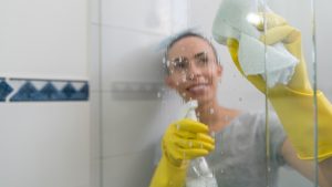 Chica limpiando los cristales de la ducha // Getty